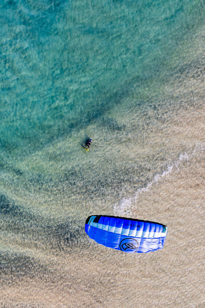 Drone view of kitesurfer launching kite in shallow turquoise water at Risco del Paso lagoon with Surfers Island, Fuerteventura