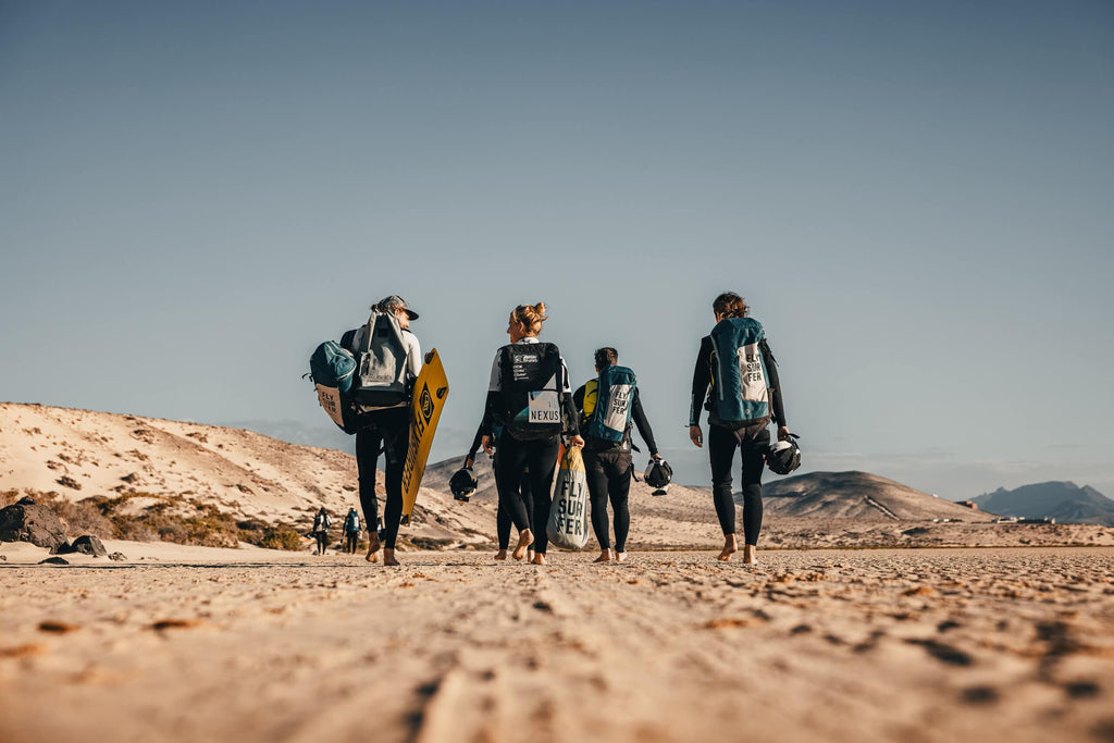 Kitesurf students from Surfers Island walking through the dunes of Fuerteventura with boards and harnesses after a beach session