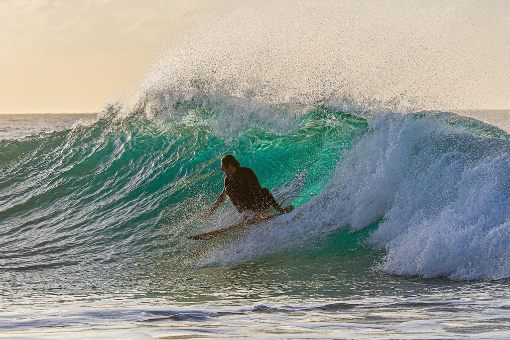 Advanced surfer carving inside a breaking wave at sunset with Surfers Island, Fuerteventura