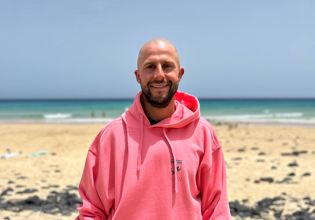 Surf-, Kitesurfinstructor Sander in front of the Surfers Island Station at the beach of Morro Jable wearing Surfers Island Hoodie Merch